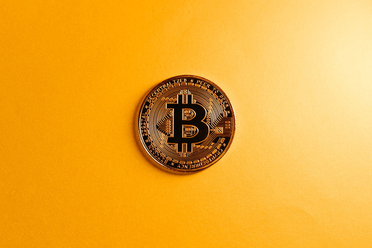A close-up of a Bitcoin coin on a bright yellow background, symbolizing digital currency.